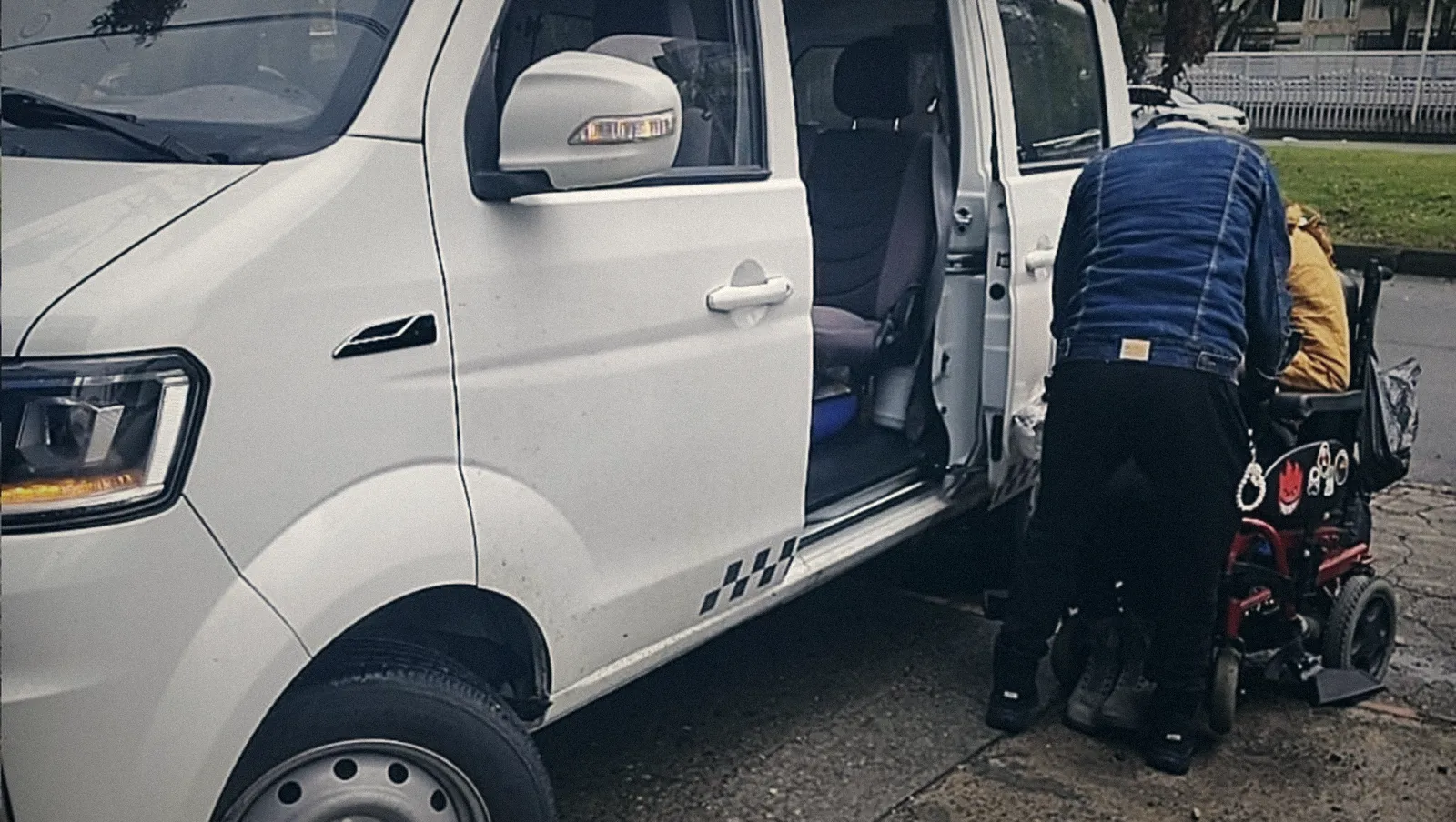 Conductor GO ayudando a un paciente en silla de ruedas eléctrica junto a la van