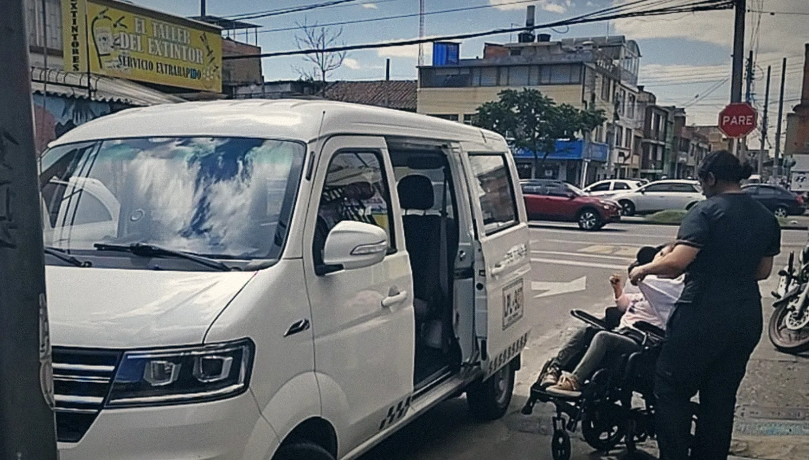 Van GO estacionada en la calle mientras una cuidadora acerca a una paciente en silla de ruedas